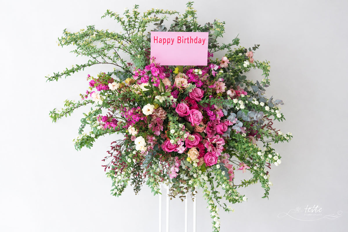 ピンク系のスタンド花(Happy Birthday の札)
